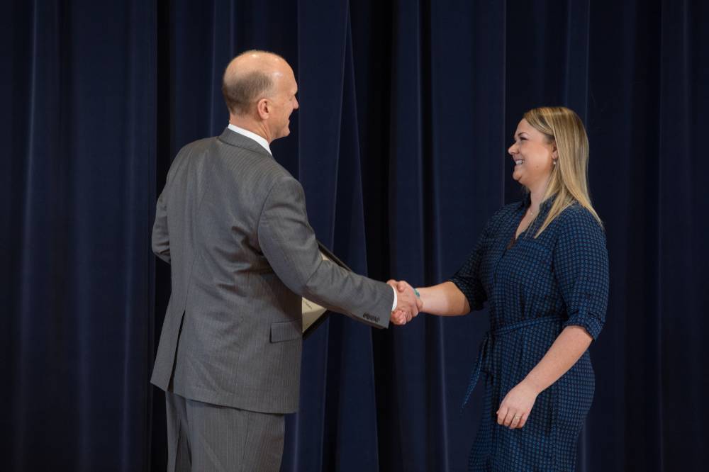 Woman smiling shaking hands with Dean Potteiger as she receives her award